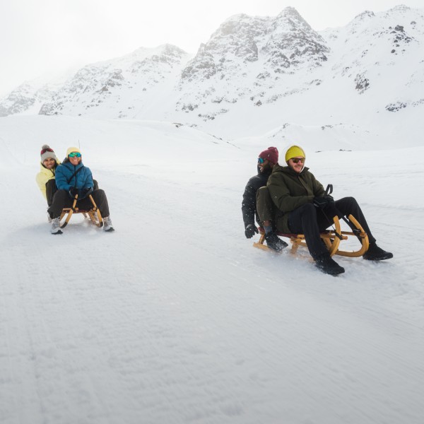 Three people sitting on a sledge in the snow